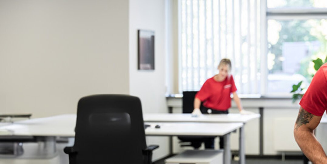 Reinigungskraft saugt Büro 