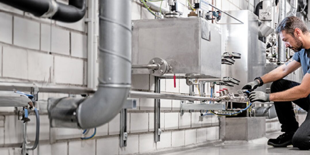 Gebäudetechniker von Dussmann repariert Rohr